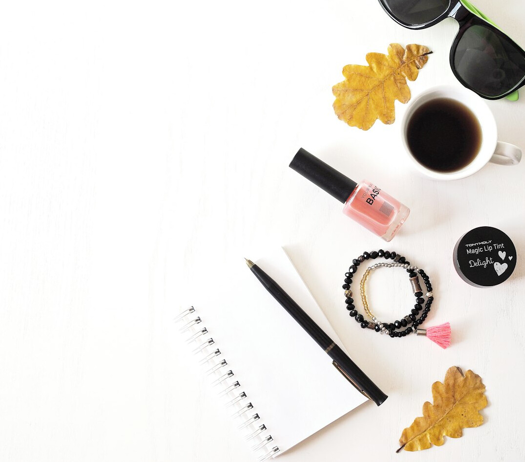 Top view of a white desk with notebook, pen, smartphone and coffee cup
