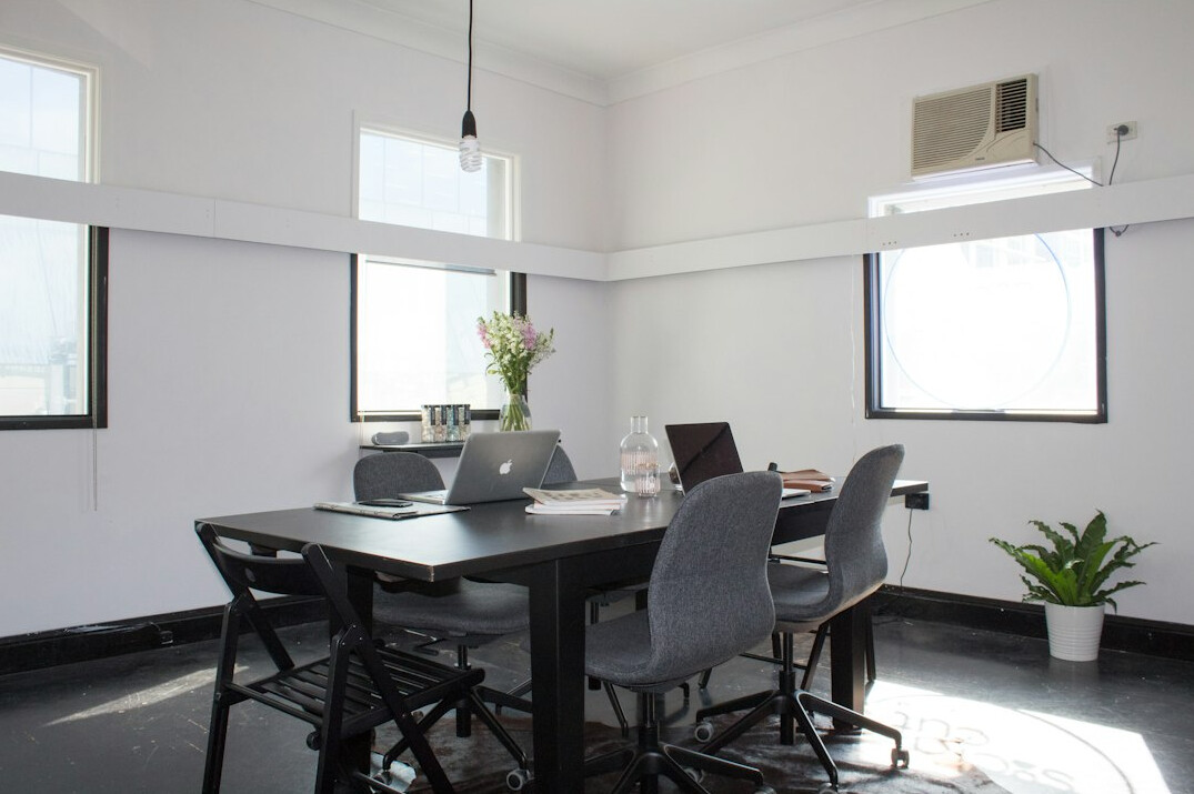 Bright modern meeting room with a wooden table, notebooks, pens and coffee cups